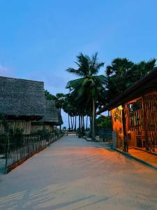 a street with a building and palm trees in the background at Borassus Nature Huts by ABC Leisure's group in Jaffna