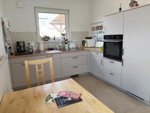 eine Küche mit weißen Schränken und einem Holztisch in der Unterkunft FeWoMeißner in Wittingen