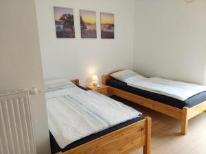 Zwei Betten in einem Schlafzimmer mit zwei Bildern an der Wand in der Unterkunft FeWoMeißner in Wittingen