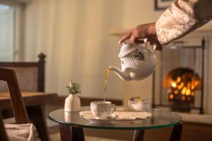 a person pouring coffee into a cup on a table at Singell Tea Estate - A CGH Earth Experience in Darjeeling