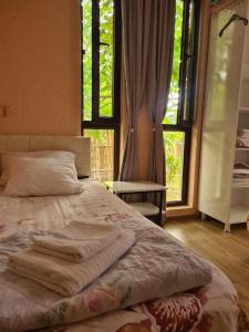 a bed with two towels on it in a room with windows at MAG house in Shekhvetili