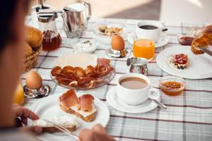 a table topped with plates of food and cups of coffee at Gass-Hof in Caldaro