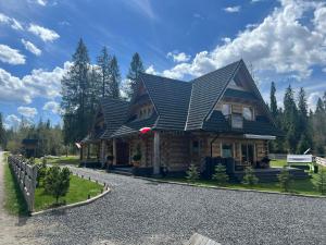 a house with a black roof on a gravel road at Zacny Lasek in Poronin