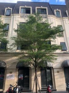 a tree in front of a building with motorcycles parked in front at Gemstay Hotel Hue in Thôn Trường Giang