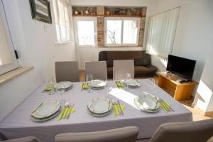 a dining room table with plates and glasses on it at Apartmani Jasna in Omiš