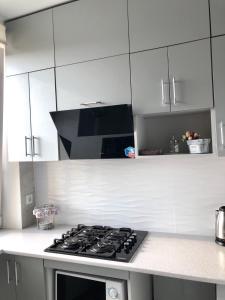 a kitchen with a stove and white cabinets at New Marine Apartment in Yuzhne +7 photos