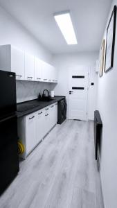 a large kitchen with white cabinets and black appliances at Przystanek Wałbrzych in Wałbrzych +3 photos