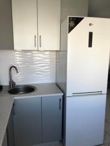 a kitchen with a white refrigerator and a sink at New Marine Apartment in Yuzhne
