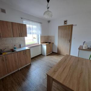 a kitchen with wooden cabinets and a wooden table at Pokoje u Teresy Rewa in Rewa