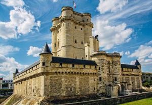 a castle building with a flag on top of it at Charming Duplex by Vincennes Castle in Vincennes