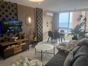 a living room with a couch and a tv and a table at BENILOVE en playa VUE MER Panoramique in Benidorm