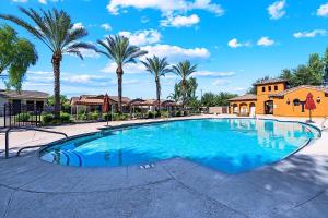a large swimming pool with palm trees and a house at Getaway at Power Ranch in Gilbert