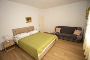 a bedroom with a green bed and a couch at Apartmani Jasna in Omiš