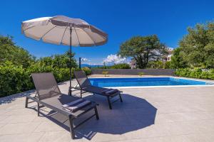 two chairs and an umbrella next to a pool at Villa MARIS with private pool in Sveti Vid-Miholjice