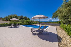 two chairs and an umbrella next to a swimming pool at Villa MARIS with private pool in Sveti Vid-Miholjice
