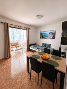 a living room with a table and chairs and a couch at Perfectly located apartment with pool in Playa de las Americas