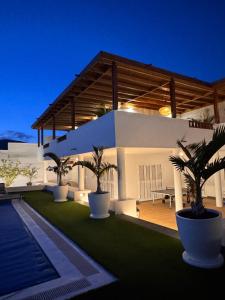 a white house with palm trees in front of it at Villa Dedalos - Spacious luxury Villa with heated pool in Puerto Calero in Puerto Calero