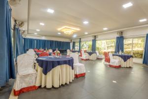 a banquet hall with tables and chairs and blue drapes at Mainland Resorts & Spa by Kolaahalam in Yercaud +132 photos