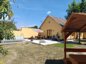 a house with a table and an umbrella at Tengelice-ház in Réde