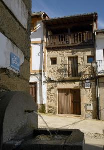 un antiguo edificio de piedra con balcón en una calle en Apartamentos Rurales Tía Josefa, en Tornavacas