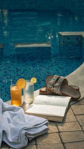 a table with a book and two glasses of orange juice at Mainland Resorts & Spa by Kolaahalam in Yercaud
