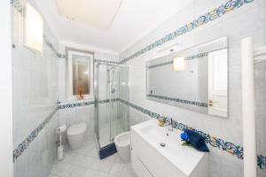 a white bathroom with a sink and a mirror at Villa La Panoramica Sea View in Capri