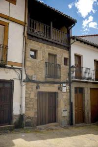 Edificio de piedra antiguo con 2 puertas y balcón en Apartamentos Rurales Tía Josefa en Tornavacas