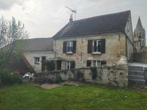 an old stone house with a stone wall and a church at Gite du Colombier in Santeuil