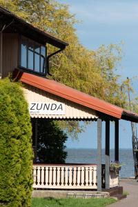 ein Gebäude mit einem Schild darauf neben dem Wasser in der Unterkunft Zunda in Nida