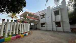 a white building with a fence with colorful columns at Sangeetha Private Pool Villa in Auroville