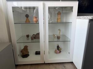 a white cabinet with glass shelves with vases at Appartamenti Lago di Como in Valbrona