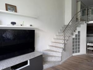 a staircase in a living room with a flat screen tv at Appartamenti Lago di Como in Valbrona