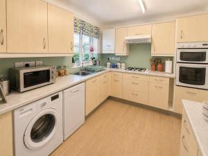a kitchen with a washing machine and a microwave at Two Ducks Cottage by NewFo dot Rest in Lyndhurst