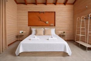 a bedroom with a large white bed in a wooden wall at Hilltop Chalet 5 in Hanioti