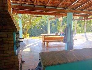 a patio with a wooden table and a bench at Linda Chácara Próxima a Monte Verde in Camanducaia