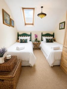 a bedroom with two beds and a chandelier at Two Ducks Cottage by NewFo dot Rest in Lyndhurst +16 photos