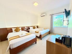a hotel room with two beds and a television at The One by Nika in Siem Reap +109 photos