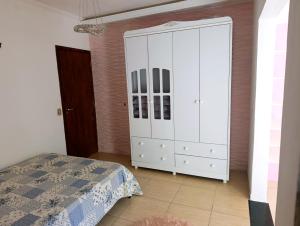 a bedroom with a bed and a large white cabinet at Linda Chácara Próxima a Monte Verde in Camanducaia +7 photos