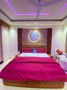 a bedroom with a large red bed with a painting on the wall at Velvet stay in Lucknow