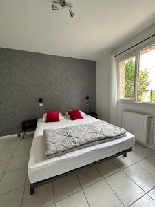 a bedroom with a bed with two red pillows at Au Trèfle Dort in Châtel-Guyon