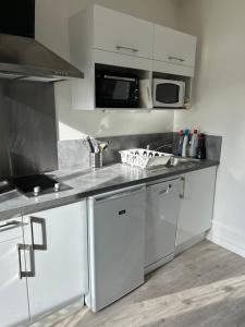 a kitchen with white cabinets and stainless steel appliances at Au Trèfle Dort in Châtel-Guyon