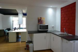 a kitchen with white cabinets and a microwave on a counter at Pavia Ostello in Pavia
