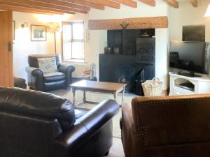 a living room with leather furniture and a fireplace at Aysgill Cottage in Hawes