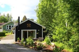 a black house with a bench in the front yard at Schwedisches Waldcottage Fluss & Wanderwege in Fristad