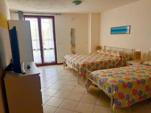 a room with two beds and a flat screen tv at Foresteria Kiki in Gravedona