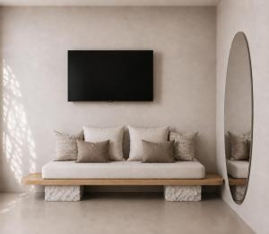 a living room with a couch and a tv on a wall at Sea Lily Suites Milos in Paleochori