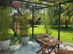 a wooden table and bench under a pergola with plants at Les Terasses d Eole in Assigny +7 photos