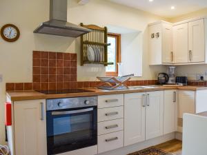 a kitchen with white cabinets and a stove top oven at Cherry Barn in Dufton