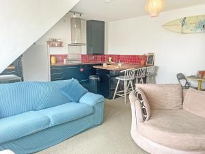 a living room with a blue couch and a kitchen at 6 Pentire Mews in Newquay