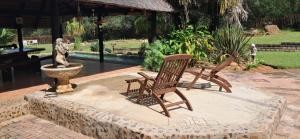 two rocking chairs and a fountain in a garden at Daisy Lodge in Barberton